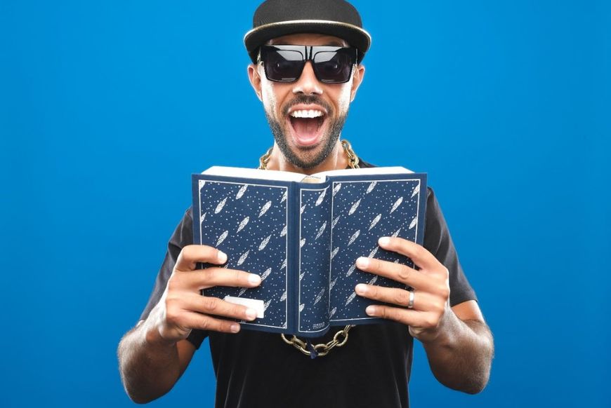 man looking at a book suprised on a blue background